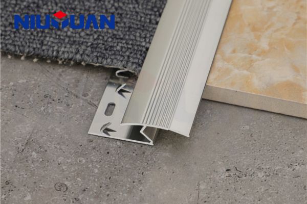 Un rail métallique avec des dents de préhension est vissé dans le sous-plancher entre le stratifié et la moquette.