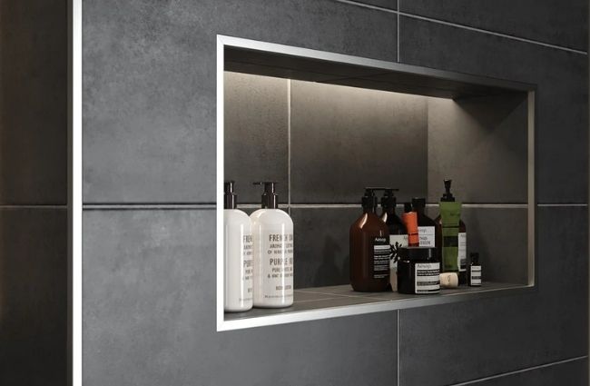 Close-up of a square aluminum tile outside corner trim protecting a shower niche from edge chipping